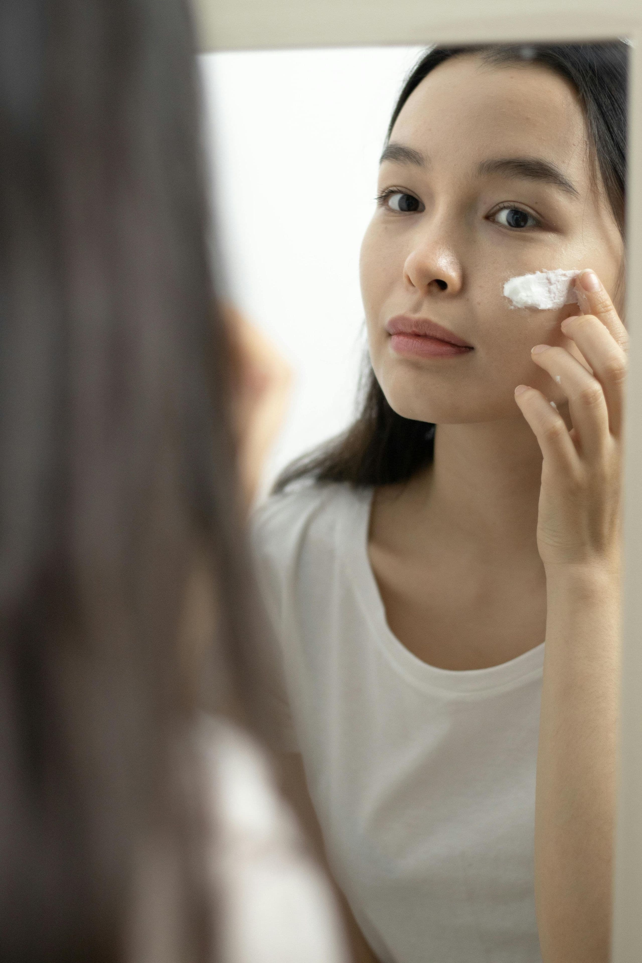 鏡の前でスキンケアをする女性